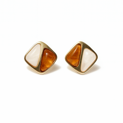 Pair of gold earrings with orange and white stones on a white background